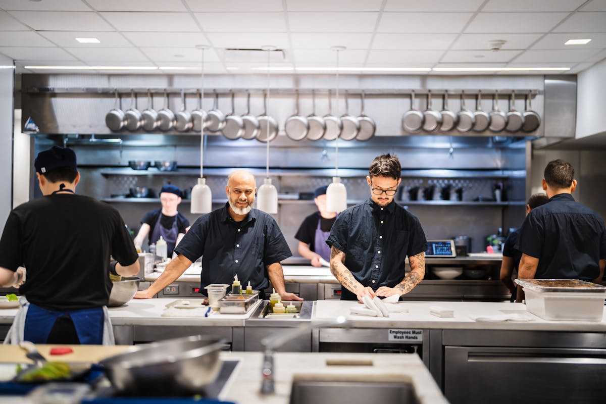 a group of people standing in a kitchen preparing food